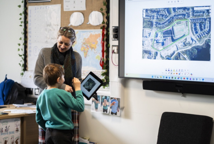 Teacher working with student using an iPad and interactive whiteboard